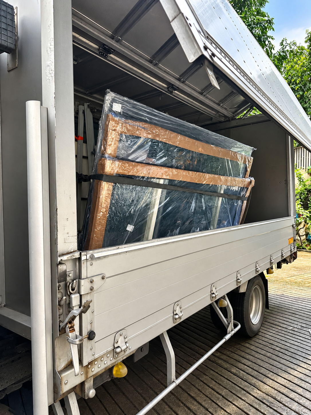 Wrapped glass and aluminium components secured with straps inside a truck.